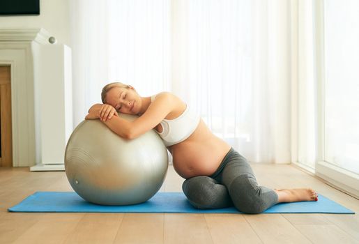 Making her pregnancy a fit and stress free one. a pregnant woman working out with an exercise ball at home