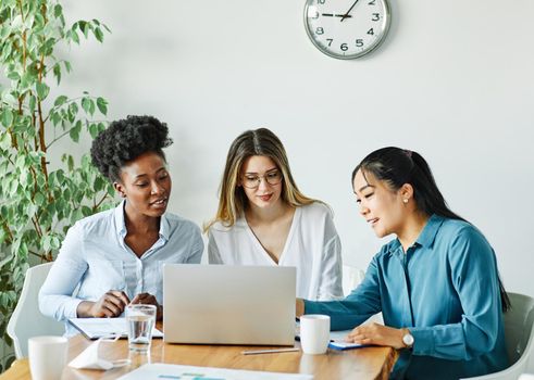 Portrait of a group of young businesswomen multiethnic working with laptop on desk and talking in a start up office