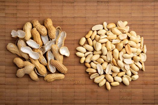 flat lay image of peeled peanuts seeds and shells on bamboo cutting table. (arachis hypogaea) Edible seeds. Healthy snack nutrition concept