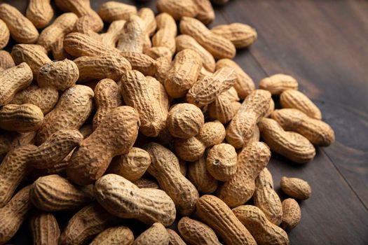 Unpeeled peanuts close up on wooden background. (arachis hypogaea) Edible seeds. Healthy snack nutrition concept