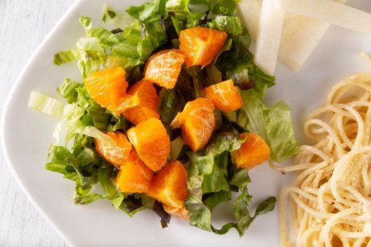 Fresh mixed lettuce and tangerine salad, accompanied by jicama "Pachyrhizus erosus" also known as Mexican yam bean or Mexican turnip. Closeup. Top View