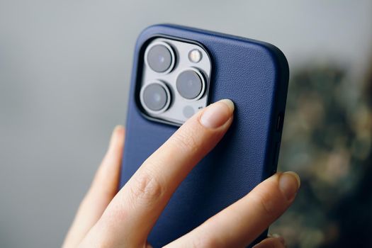 Person holds an iPhone 13 pro in a blue case. Smartphone with triple-lens camera in women's hands. Photos for advertising apps and gadgets with copy space. Bishkek, Kyrgyzstan - January 24, 2022