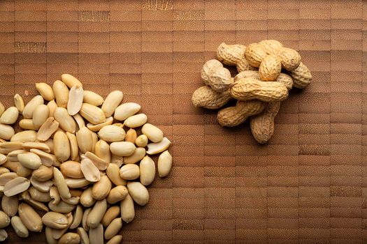 top view image of peeled and unpeeled peanuts seeds and on bamboo cutting table. (arachis hypogaea) Edible seeds. Healthy snack nutrition concept