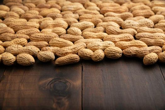 Unpeeled peanuts on wooden table background with copy space. (arachis hypogaea) Edible seeds. Healthy snack nutrition concept