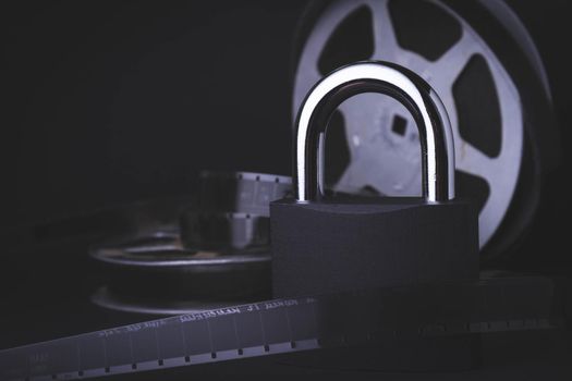 Movie screening ban. Forbidden film. Indoor cinema.Film reel and padlock on a black background. Limited screening of the film in cinemas.