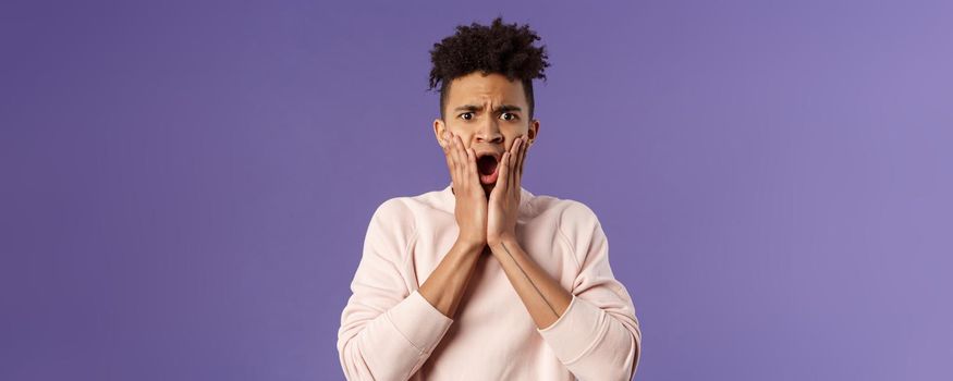 Oh gosh thats terrible. Portrait of shocked, speechless and worried young man express compassion finding out friend got in trouble, gasping open mouth and stare startled camera, touch face in shook.