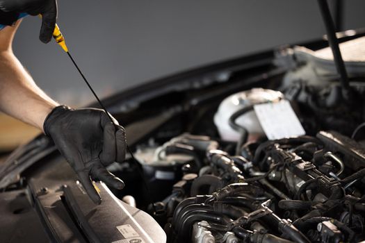 The car mechanic is checking the engine oil level. Overheating of car engine. Motor with open hood. Checking the engine oil car maintenance Remove the dipstick to view the engine oil level.