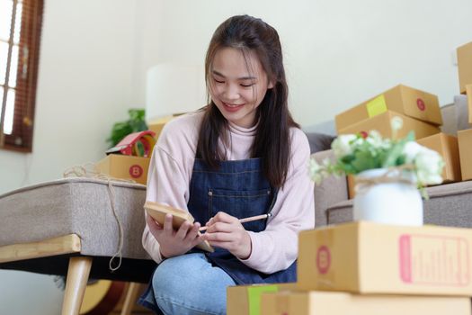 Portrait of Starting small businesses, Asian woman check online orders Selling products working with boxs freelance work at home office, sme business concepts