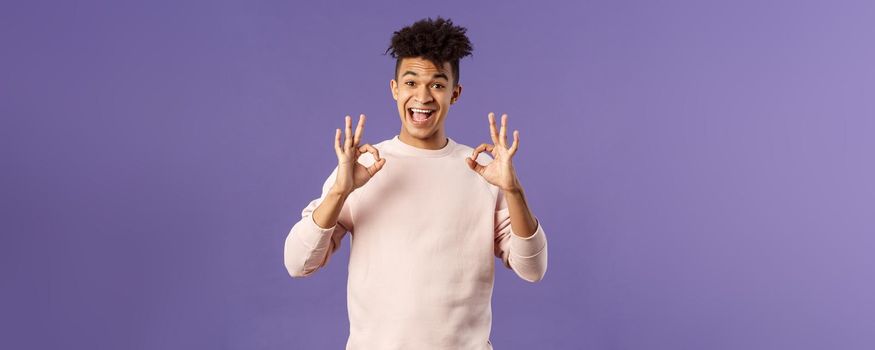 Portrait of satisfied young male student recommend online business school or education courses, give excellent feedback, show okay gesture as approve or like something really good.