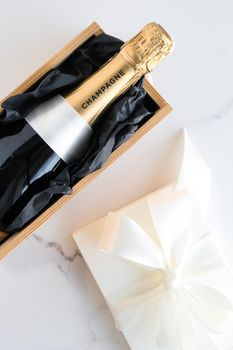 Wedding celebration, lifestyle and luxury present concept - A champagne bottle and a gift box on marble