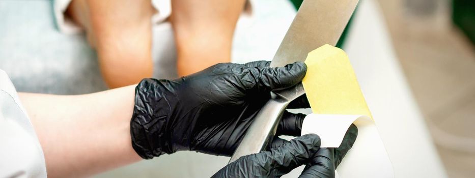The pedicure master putting on new sandpaper on the metal handle before the procedure of cleaning the foot and heel in a nail salon