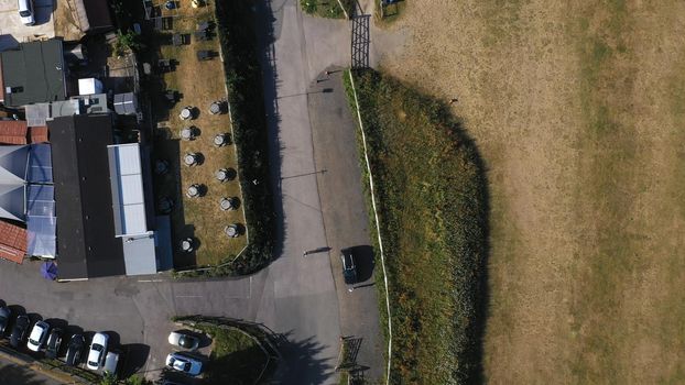Top Down Aerial View of Green and Yellow Wheat Field Farm and Greenhouses. Golden Crops During Pasture Aerial View. Agricultural Work in Summer During Drought. Grain Crisis. Nature, Harvesting, Eco