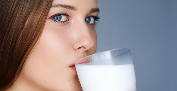 Happy young woman drinking milk or protein milk shake cocktail, healthy drink for diet and wellness concept