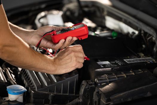 Check battery voltage with electric multimeter. Car starter battery. Professional mechanic is working in car service. Good, electrician, electricity, battery charged fully