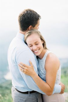 Smiling woman hugging a man while standing on a mountain. Portrait. High quality photo