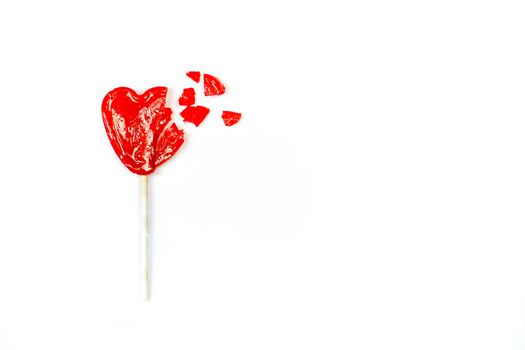 Red broken heart shaped lollipop on white background