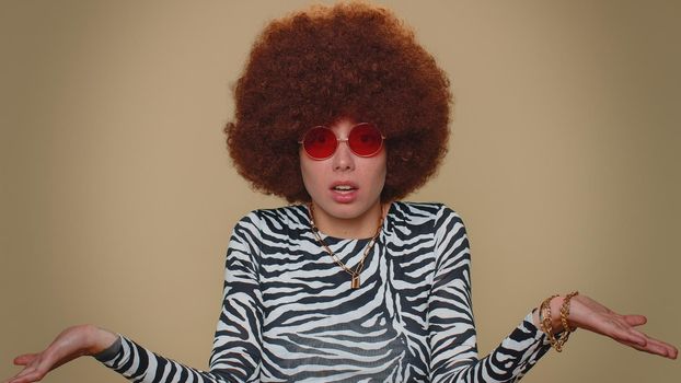 Pretty young woman raising hands in indignant expression, asking why, what reason of failure, demonstrating disbelief irritation by troubles. Adult stylish girl isolated on beige studio background