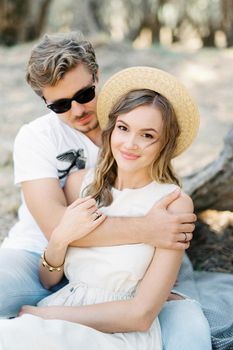 Man hugging woman in straw hat. High quality photo