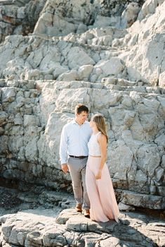 Young man and woman stand on rocks and look at each other. High quality photo