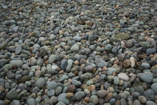 Natural rounded gravel on the seashore nature background texture pattern. Pebble beach stones background.