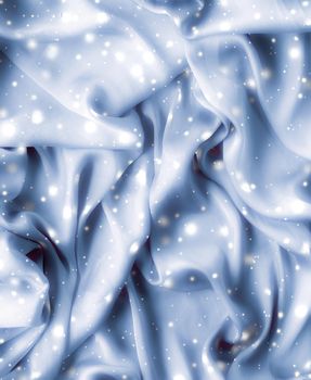 Winter fashion, shiny fabric and glamour style concept - Magic holiday blue soft silk flatlay background texture with glowing snow, luxury beauty abstract backdrop