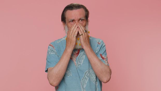 Stressed depressed mature flowered beard mature man expresses his fear and waves his hands away from danger, waving no. Scared fearful senior grandfather isolated alone on pink studio wall background