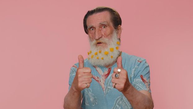 Great job, nice. Cheerful positive happy senior man showing thumbs up and nodding in approval, successful good work. Elderly stylish one grandfather on pink studio background. People sincere emotions
