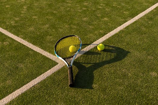 tennis balls and racket on the green grass background.