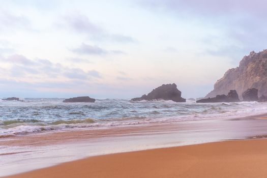 Ocean wild beach stormy weather. Praia da Adraga sandy beach with picturesque landscape background, Sintra Cascais, Portugal Vitality of blue energy and clear ocean water