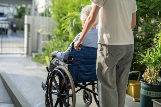 Caregiver help and care Asian senior or elderly old lady woman patient sitting on wheelchair to ramp in nursing hospital, healthy strong medical concept.