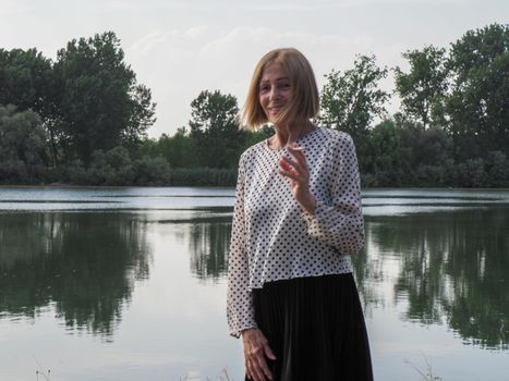female pensioner having fun and smoking a cigarette in a park - aging free and wellness concept