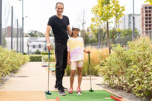 Family playing miniature golf outdoors.