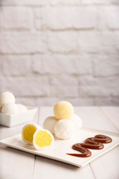 Ice cream Mochis with caramel (cajeta). Traditional Japanese dessert made from rice flour. Close up on white wooden surface with copy space.