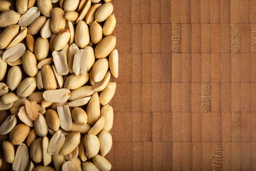 top view of peeled peanuts seeds close up on  bamboo wooden background for copy space. (arachis hypogaea) Edible seeds. Healthy snack nutrition concept