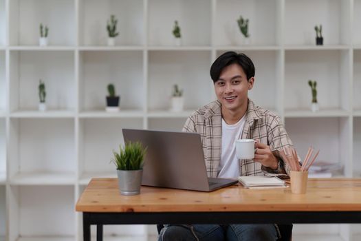 Asian man using laptop computer working at office. Creative and new idea concpet.