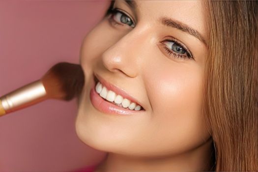 Beautiful young woman applying cosmetic powder product with make-up bamboo brush, beauty, makeup and skincare cosmetics model face portrait on pink background, closeup