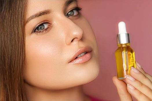 Beauty, makeup and skincare cosmetics model face portrait, woman holding skin care cosmetic essential oil bottle with dropper, luxury facial care product mockup