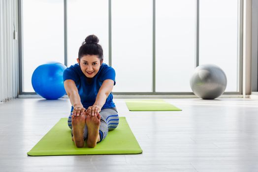 Asian young woman wearing sportswear doing practicing yoga sitting stretching leg position indoor studio. female sport fit workout concept