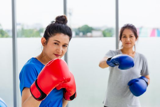 Asian lifestyle adult and young woman smiling sports fitness boxer wearing gloves practicing kick on boxing in sportswear work out indoor yoga studio, sport healthy workout concept