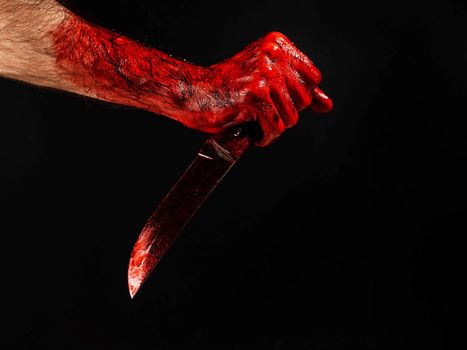 Man holding knife with bloody hand on black background