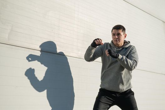 Caucasian man in hoodie is training boxing outdoors