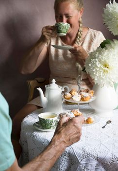 tea break in the English style, still life with flowers and donuts in the morning sun, homemade cakes, married couple drinking tea together at breakfast in english style, beautifully set table