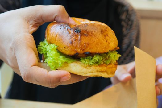 hand holding beef burger on table close up .