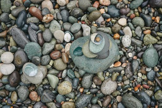 The stones, stacked one after the other, balance the rocks on the seashore. Balancing stones on a background of pebbles