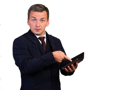 The man, dumbfounded by the news, points to the gadget with his hand. Man on a white isolated background.