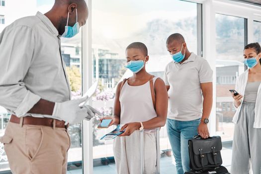 People checking in to the airport to travel during covid pandemic with face masks and luggage. Travelers showing their digital ticket and passport to the airline attendant to board the airplane