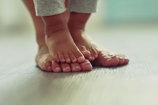 Little feet make my life so very sweet. an unrecognizable mothers feet and her childs feet at home