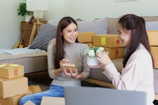 Portrait of Starting small businesses, two Asian woman check online orders Selling products working with boxs freelance work at home office, sme business concepts