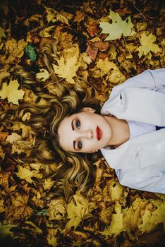 Smiling happy womanl portrait. lying in autumn leaves