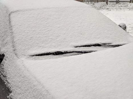 Closeup image of frosen car wipes lying on windshield.